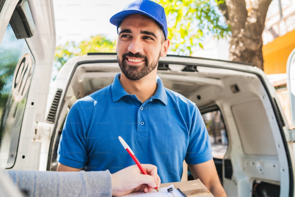 Portrait of a delivery man carrying packages while customer putting signature in clipboard. Delivery and shipping concept.
