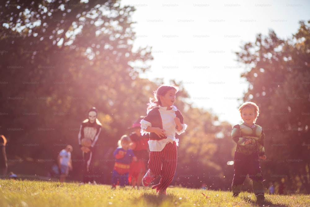 Niños con trajes de Halloween corriendo por la naturaleza. Enfoque en primer plano.