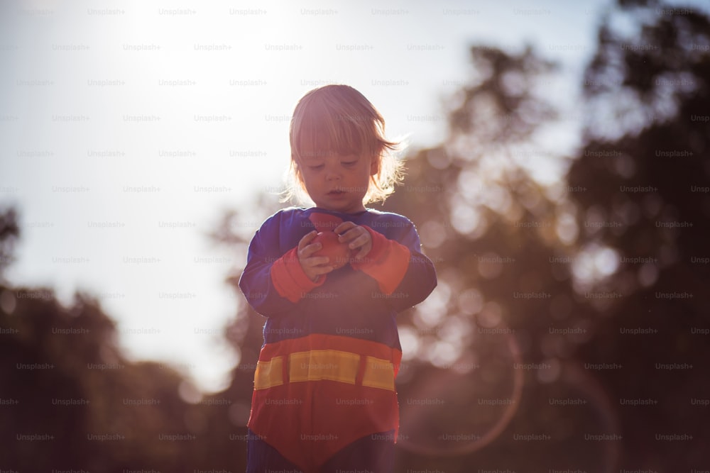 カボチャを持ったスーパーヒーローのスーツを着た小さな男の子。