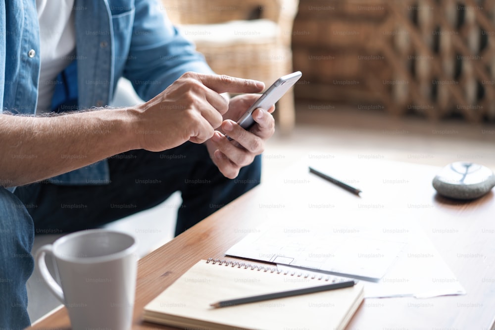 Closeup of man using smartphone device while chilling on sofa a home, typing an sms message