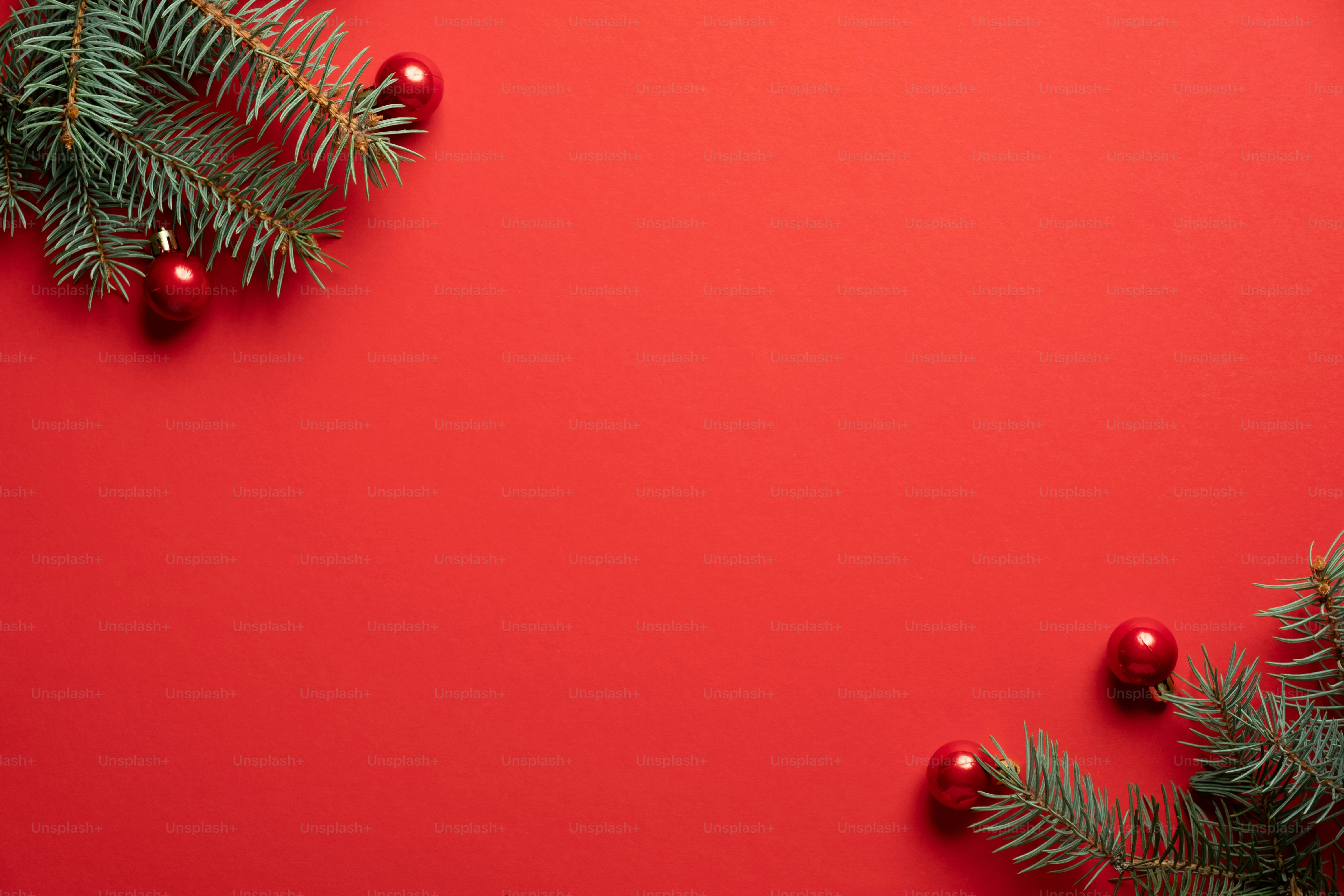 Christbaumzweige und rote Kugeln Dekoration auf rotem Hintergrund. Weihnachtsgrußkarte, Rahmen, Banner-Mockup. Flaches Lay, Draufsicht, Kopierraum.