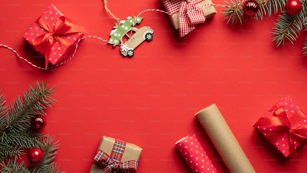 ヴィンテージのクリスマスデコレーション、ギフト、包装紙、赤いテーブルの上のモミの木の枝。クリスマス、新年、冬休みの準備コンセプト。フラットレイ、上面図、コピースペース。