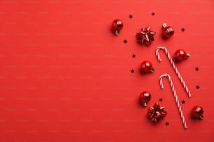 Red Christmas background with red baubles decoration, candy canes and confetti. Xmas greeting card mockup.