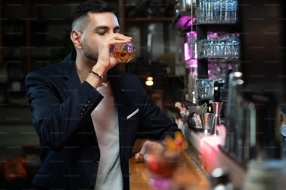 Porträt eines kaukasischen Mannes, der an der Bartheke sitzt und alkoholische Getränke trinkt