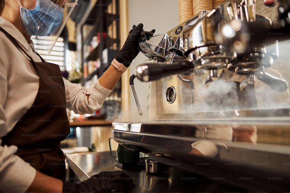 Ritratto di vista laterale del barista che prepara la bevanda del caffè per l'ospite del caffè