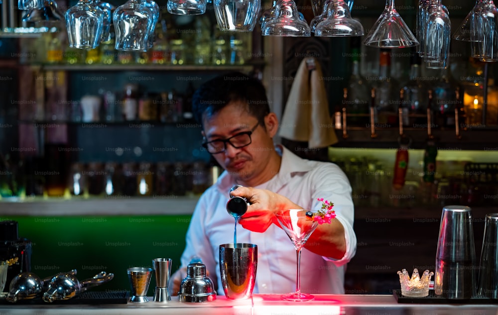 Male bartender pouring liquor alcoholic drink into cocktail shaker