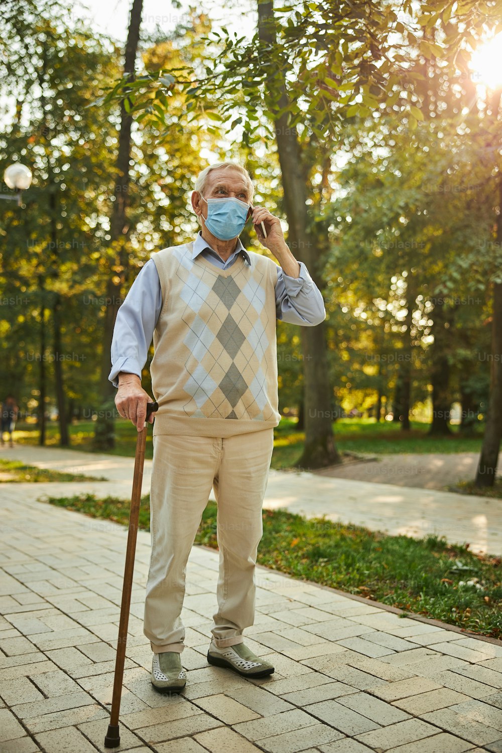 Full length portrait of handsome senior male in casual clothes walking in the city autumn park