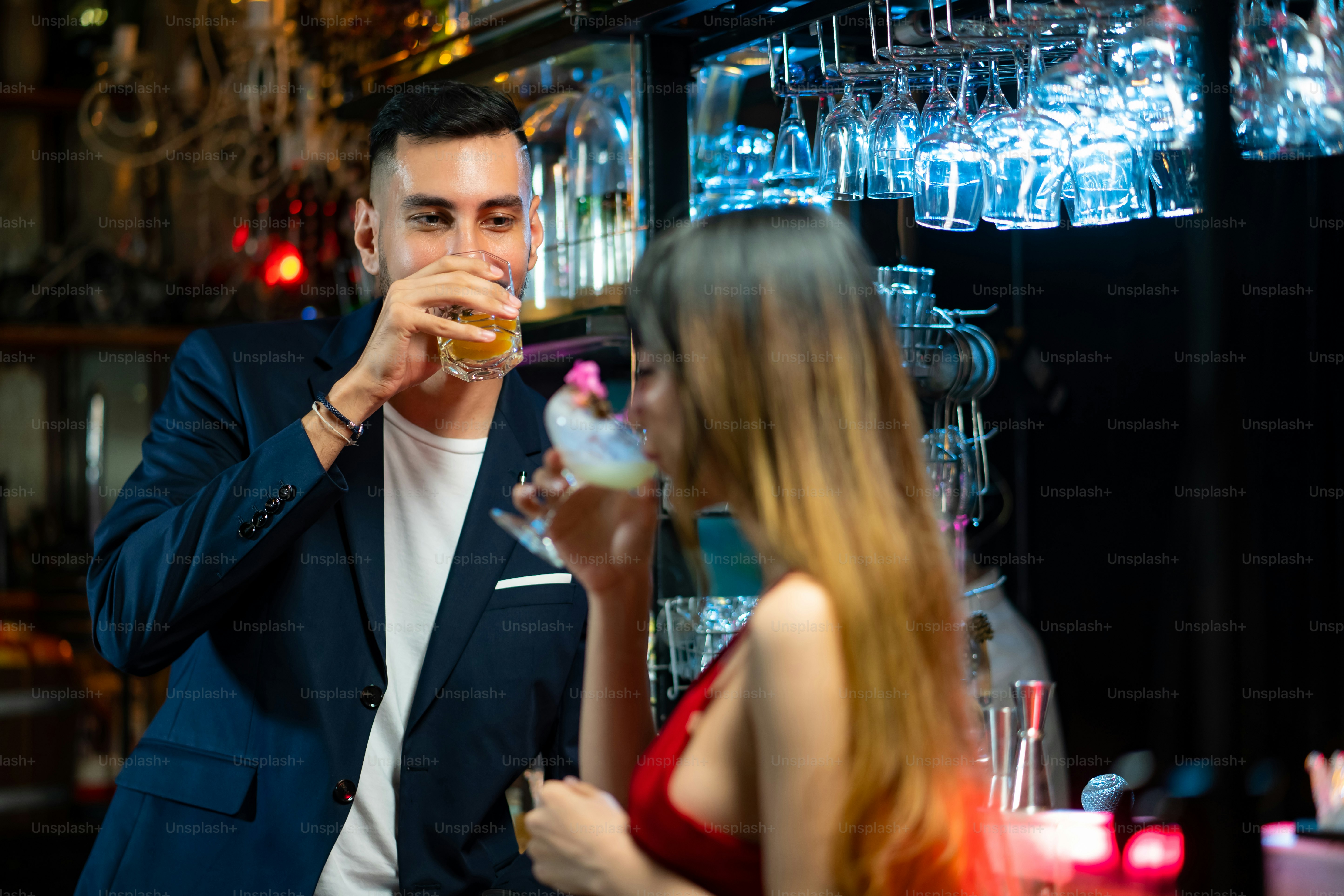 Portrait of caucasian man talking to beautiful asian woman with drinking cocktail drink at bar