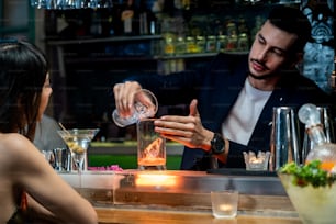 Male bartender pouring making alcoholic drink to female customer