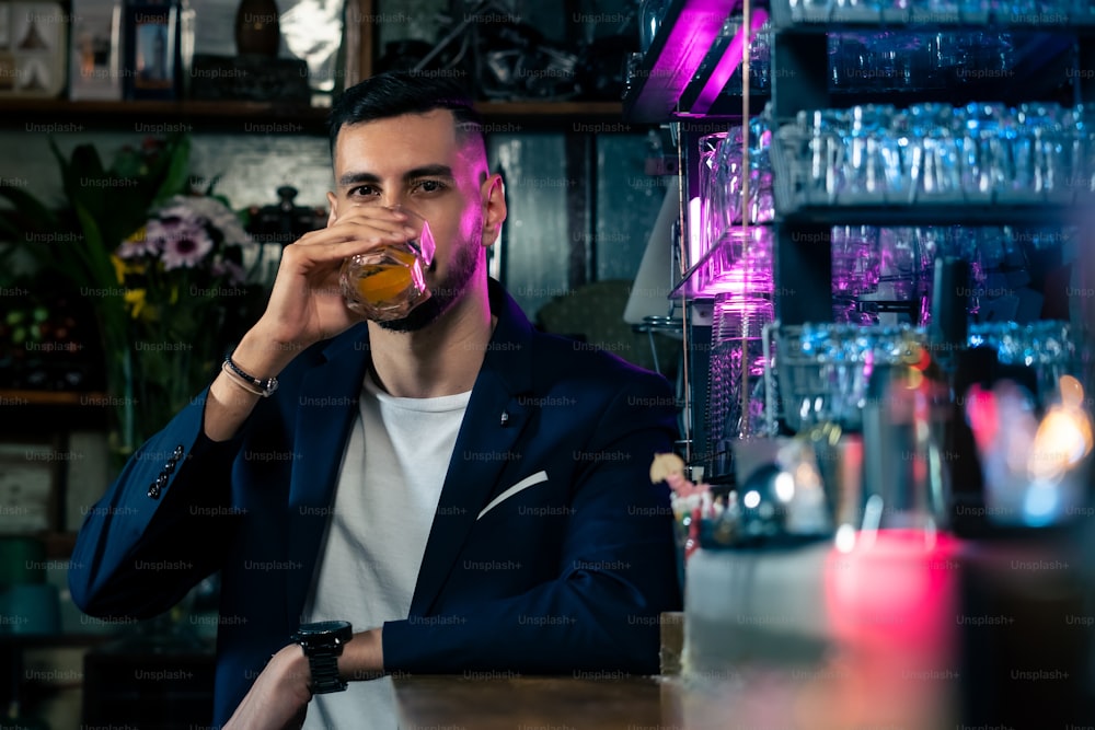 Porträt eines kaukasischen Mannes, der an der Bartheke sitzt und alkoholische Getränke trinkt