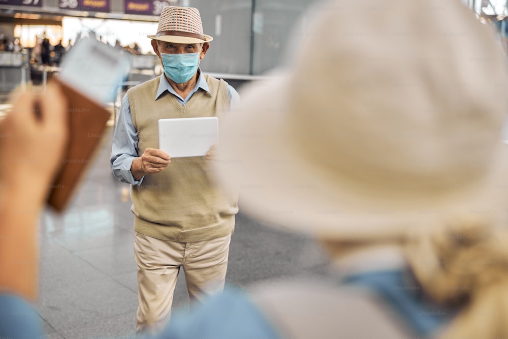 Un retraité avec une pancarte à la main rencontre son invitée au terminal de l’aéroport