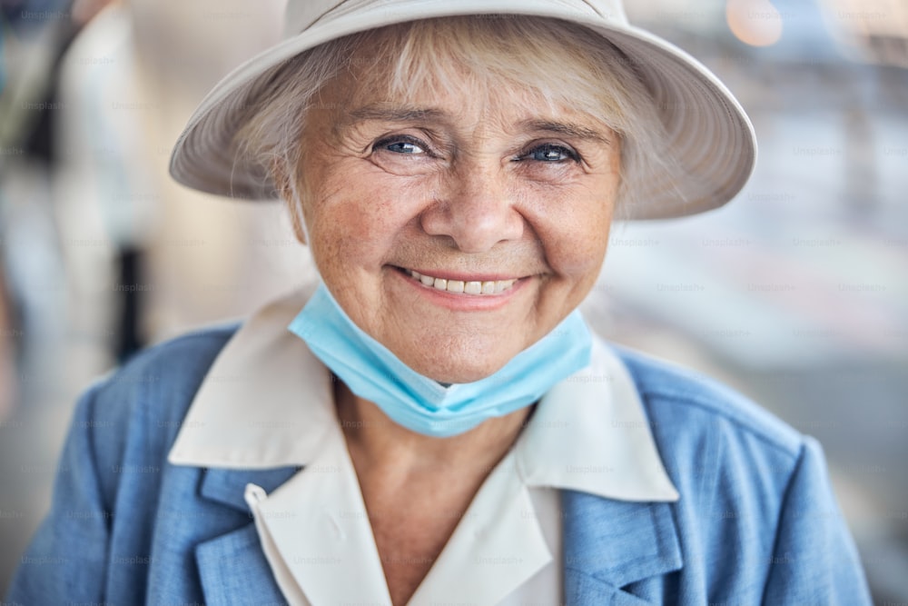Close up portrait of a pleasant joyful lady with a face mask around her chin looking ahead