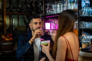 Porträt eines kaukasischen Mannes, der mit einer schönen asiatischen Frau mit einem Cocktailgetränk an der Bar spricht