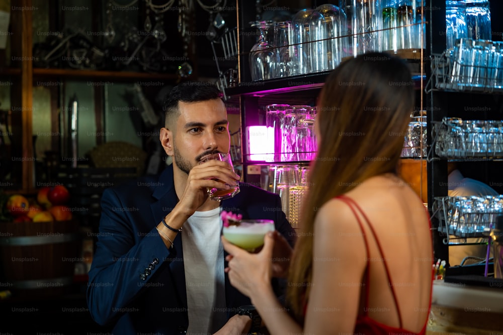 Portrait d’un homme caucasien parlant à une belle femme asiatique avec boire un cocktail au bar