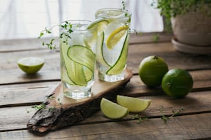 Copo de coquetel de pepino ou mocktail, bebida refrescante de verão com gelo triturado e água com gás no fundo de madeira.