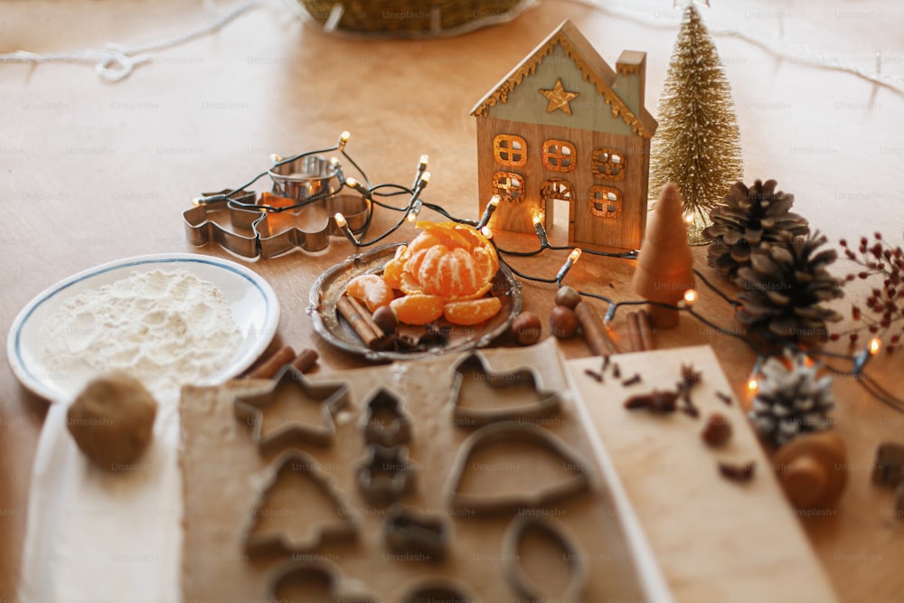 Festive christmas decorations on rustic table with raw gingerbread dough with metal cutters, spices, oranges, flour. Christmas holiday advent