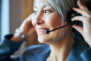 Close up of beautiful female worker in headphones looking away and smiling