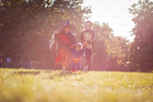 Three kids walking trough nature in Halloween suits.