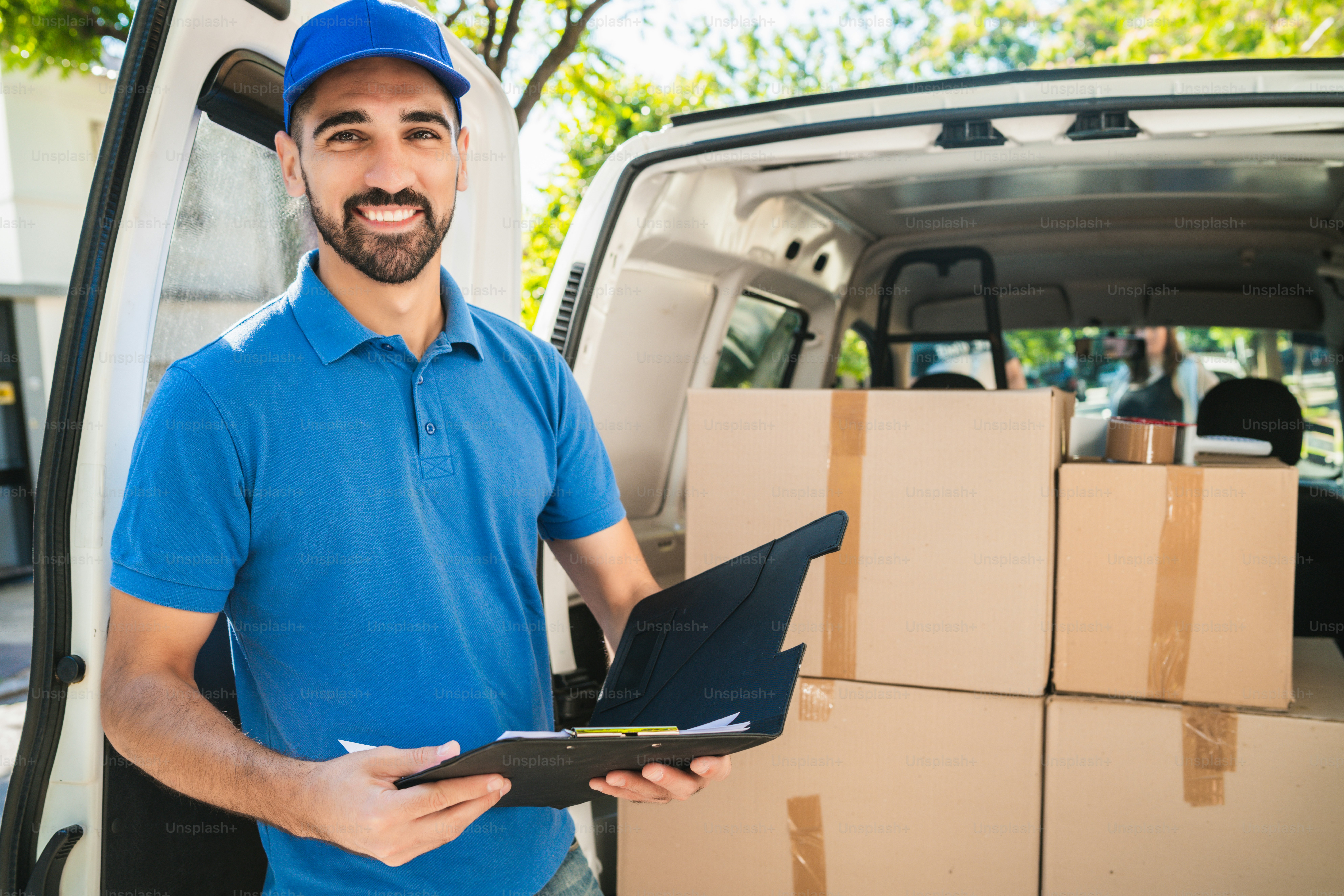 Portrait of a delivery man carrying packages while making home delivery ...