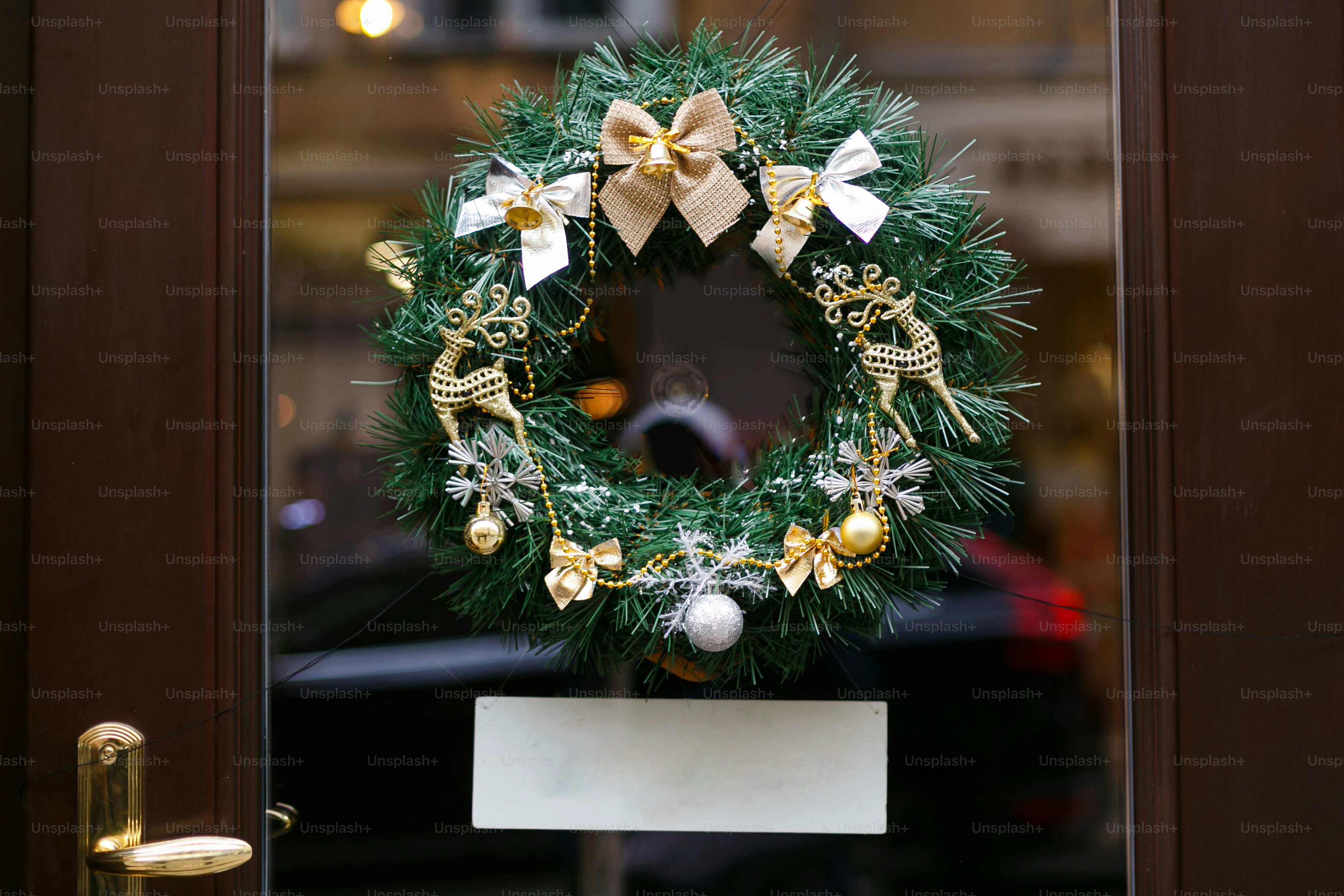 Stylish christmas wreath with golden bow and reindeer ornaments, modern decor on store front with copy space banner. Christmas festive street decor, holiday winter fair. Merry Christmas