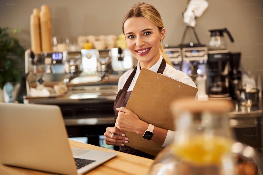 Close up portrait of elegant Caucasian woman working in the coffee shop at the laptop and posing at the photo camera