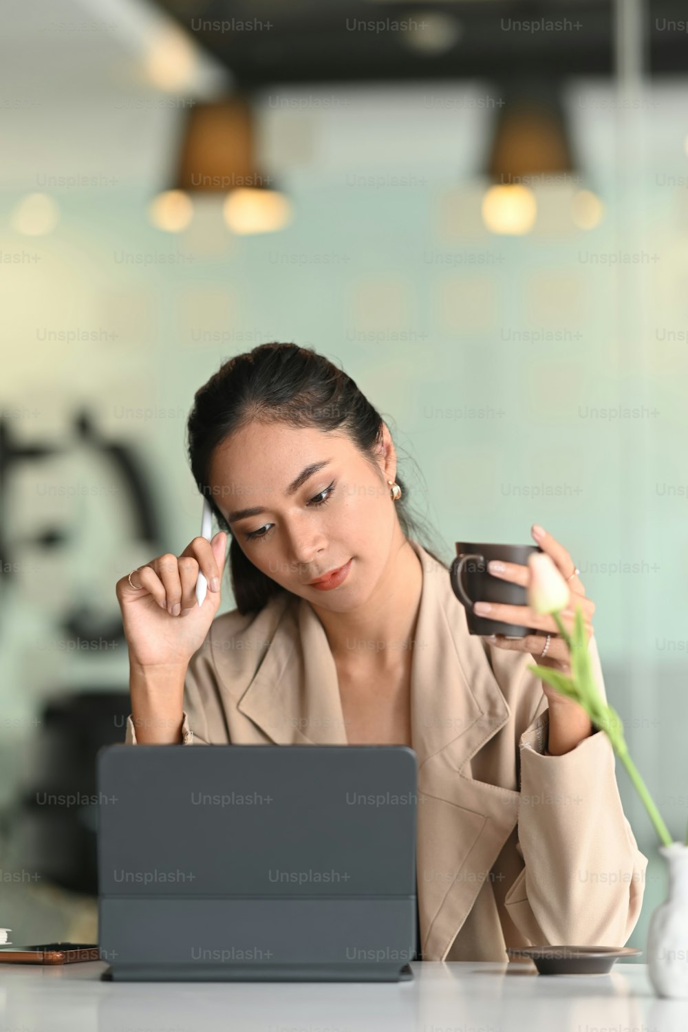 Portrait of  young businesswoman drinking coffee and working on computer tablet in office.