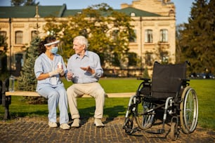 Uomo anziano con una sedia a rotelle accanto a lui che prende la medicina quotidiana all'aperto la casa per gli anziani