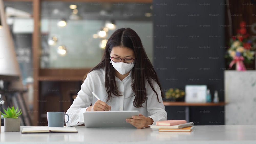 Portrait of female office worker wearing mask while working in office