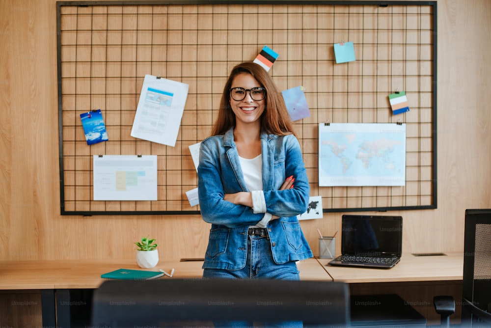 Femme d’affaires attrayante à lunettes debout dans le bureau moderne.