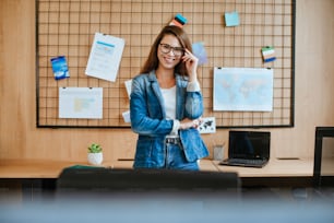 Attractive business woman in glasses standing in the modern office talking with cellphone.