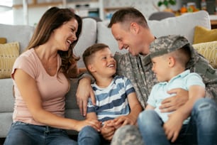 가족과 함께 바닥에 앉아 있는 행복한 군인. 아이들과 함께 집에서 즐기는 군인과 그의 아내