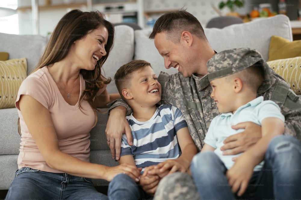 Happy soldier sitting on the floor with his family. Soldier and his wife enjoying at home with children