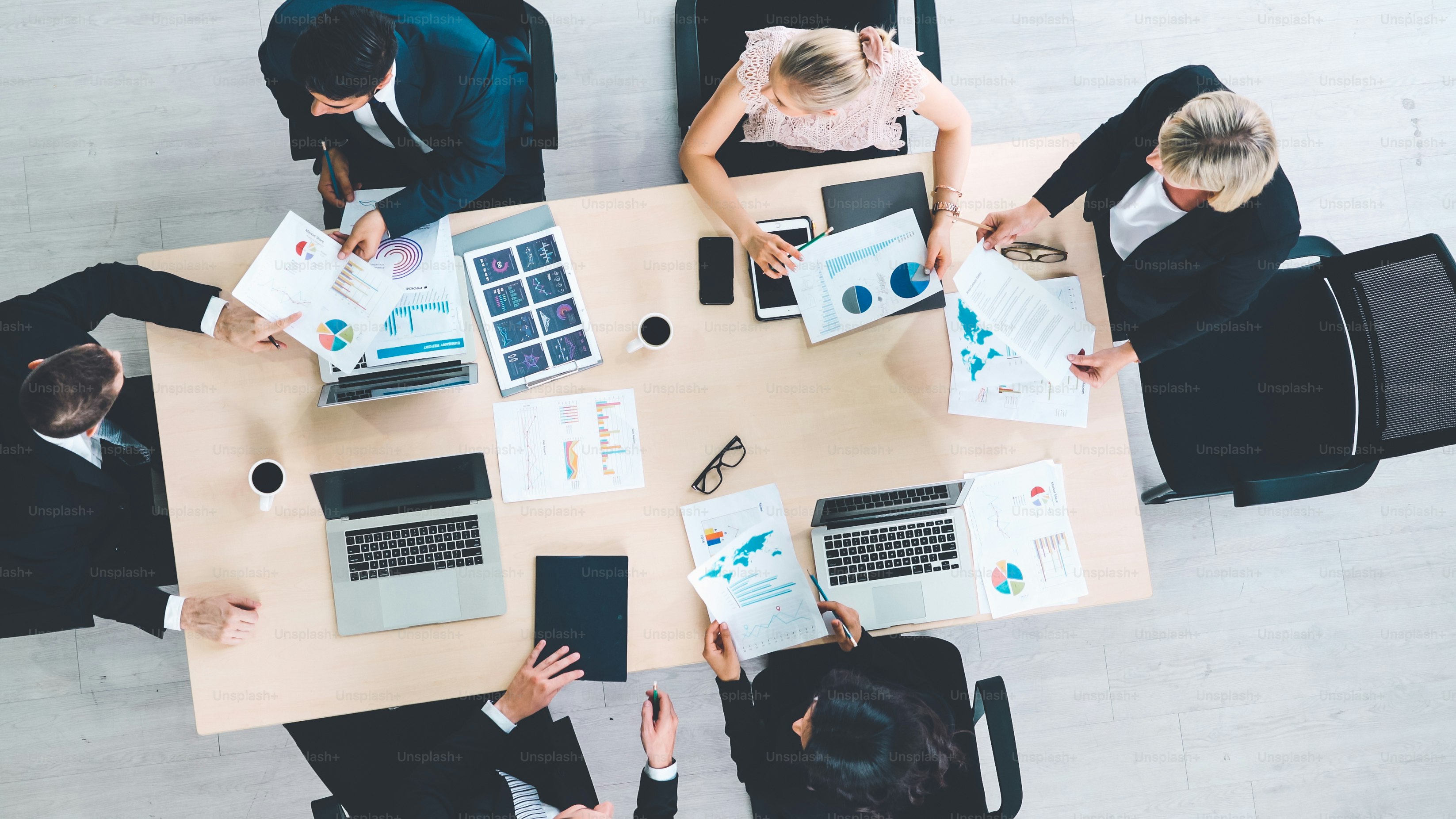 Geschäftsleute-Gruppentreffen aus der Draufsicht im Büro aufgenommen. Beruf Geschäftsfrauen, Geschäftsleute und Büroangestellte, die in einer Teamkonferenz mit Projektplanungsdokument auf dem Besprechungstisch arbeiten.