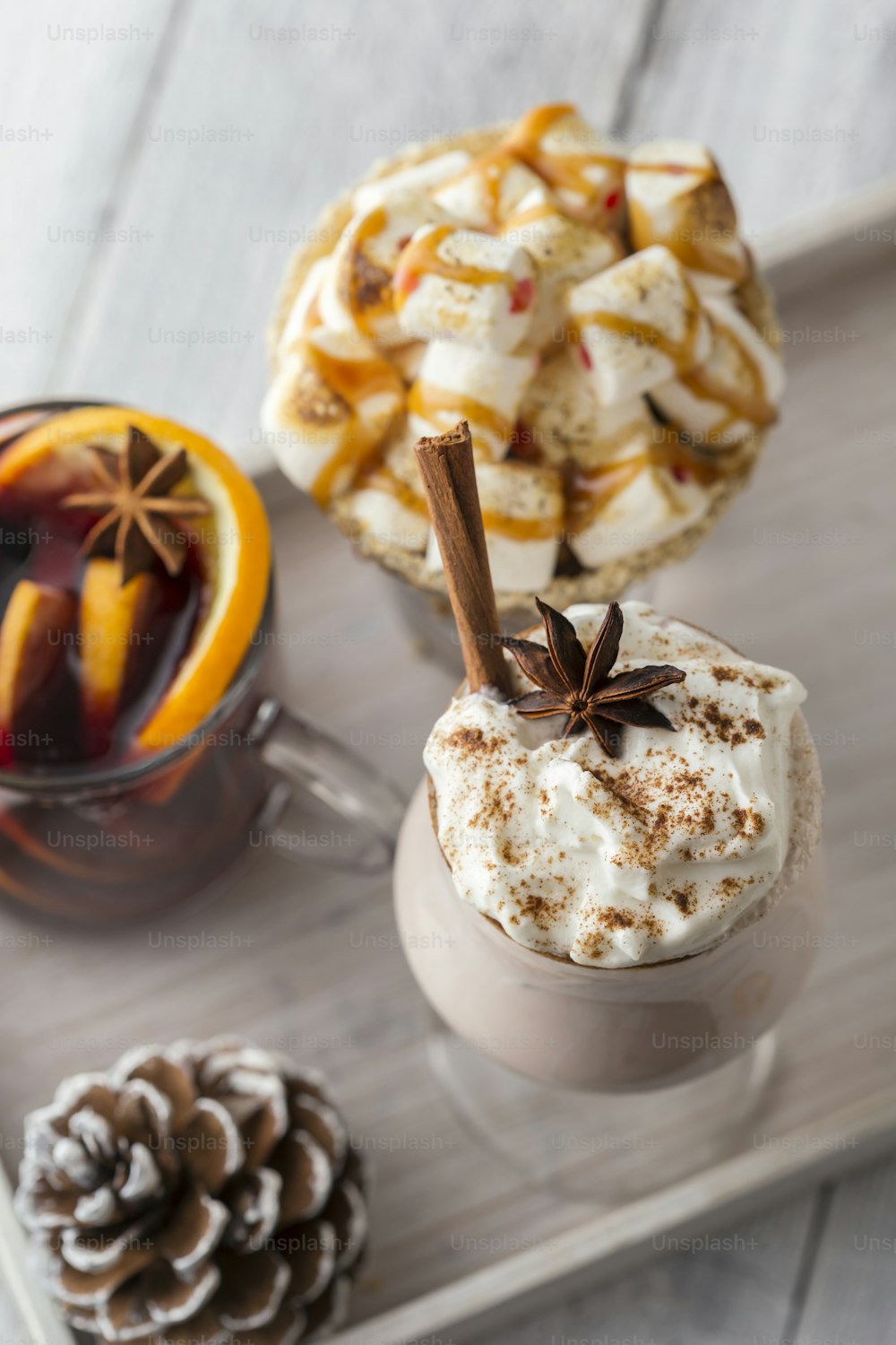 High angle view of three traditional winter Christmas time cocktails - mulled wine, hot chocolate and eggnog served on rustic wooden tray