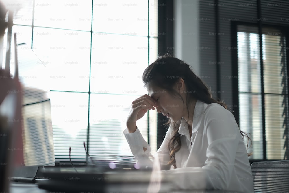 Aufnahme einer jungen Frau, die bei der Arbeit im Büro stressig ist, Office-Syndrom-Konzept.