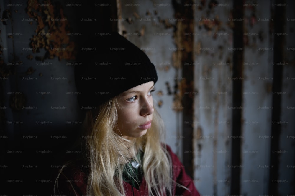 Retrato da vista frontal da menina adolescente loira em pé dentro de casa no prédio abandonado.