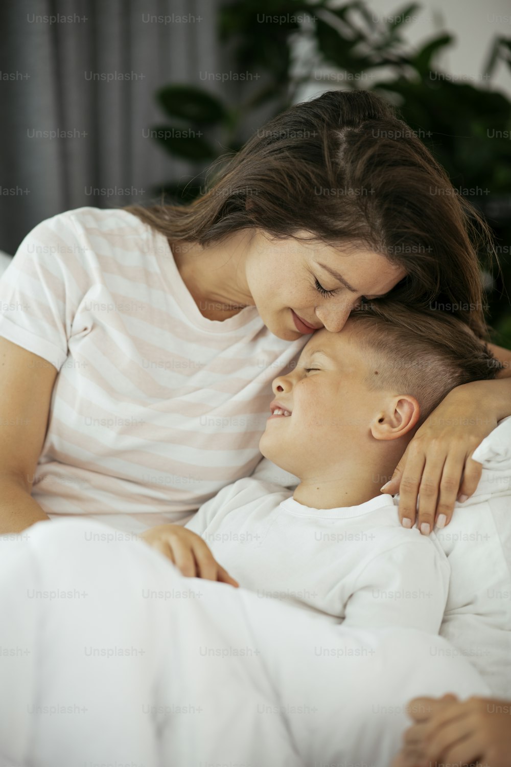 Mère et fils profitant au lit. Femme heureuse avec son fils se détendant au lit.
