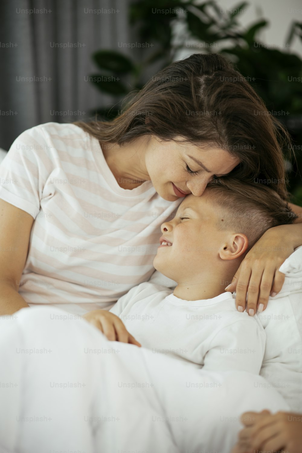 Madre e hijo disfrutando en la cama. Mujer feliz con hijo relajándose en la cama.