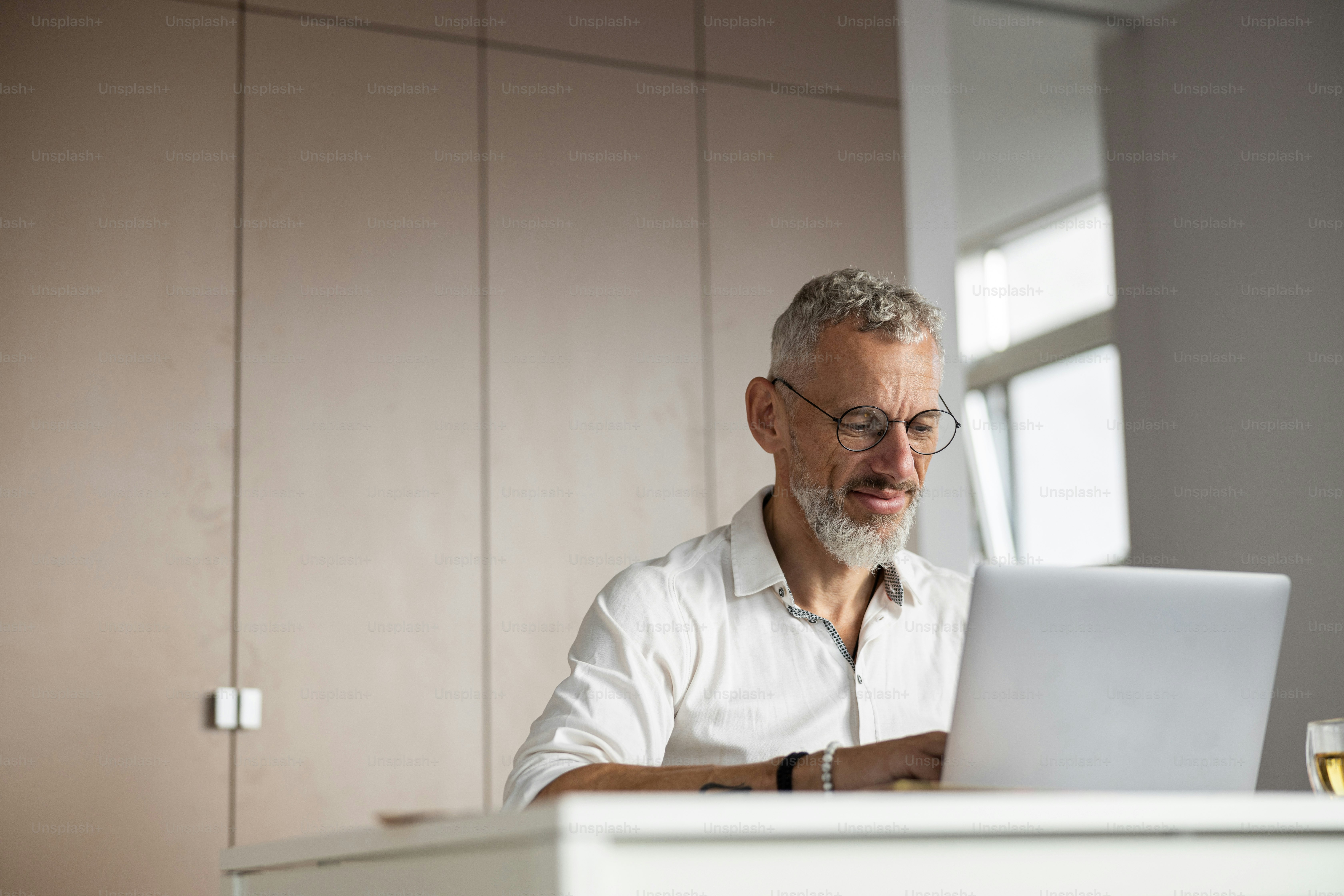 Responsible businessman in eyeglasses on a chair operating his laptop while performing his job