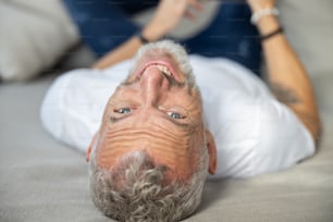 Close-up photo of a smiling man hanging his head from a sofa edge