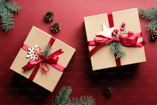 Caixas de presente de Natal vintage decoradas laço de fita vermelha e ramos de abeto no fundo vermelho marsala. Conceito de presente de Natal.
