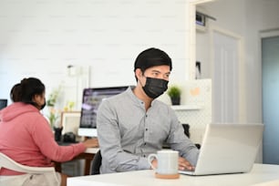 Young team of photographer with face mask are working in a professional studio.