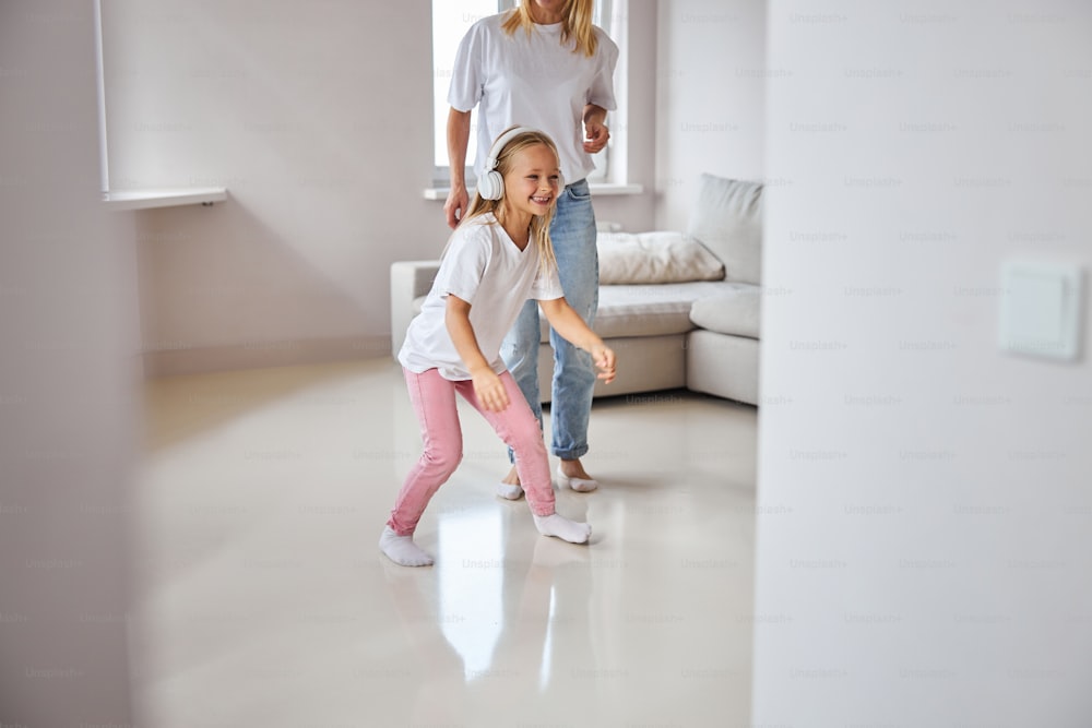Retrato de cerca de una pequeña hija sonriente feliz jugando con mamá mientras pasa el fin de semana en un gran apartamento moderno