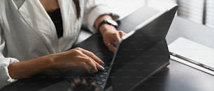 Cropped shot of businesswoman working with computer tablet on black wooden table in modern office.