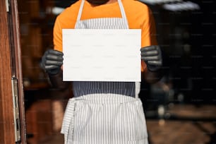 Afro American man in sterile gloves holding blank mockup placard