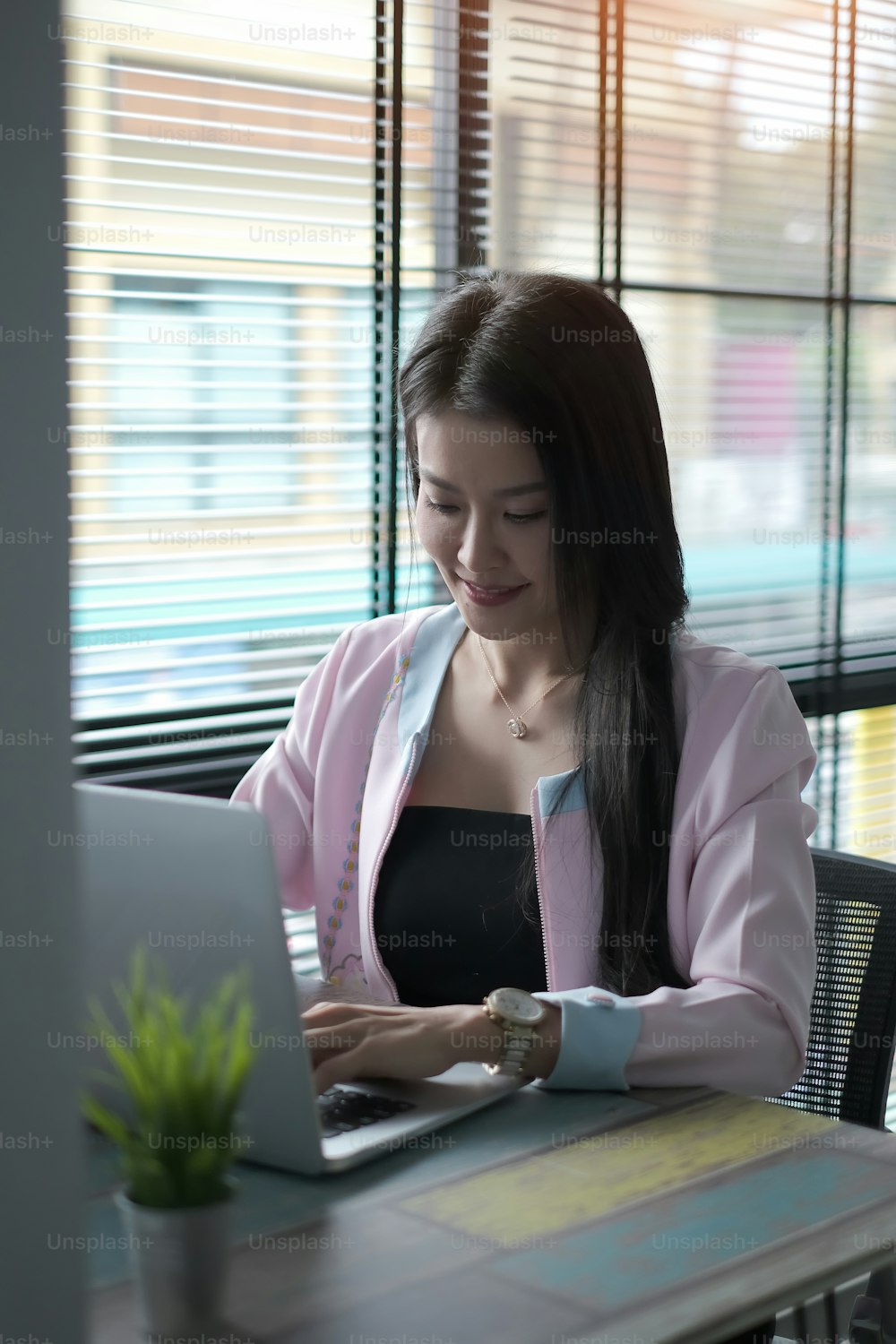 Portrait of attractive businesswoman working in office with computer laptop and sitting by the window.