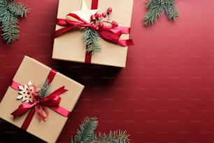 Christmas gift boxes with red ribbon bow and decorations on marsala red background. Flat lay, top view. Christmas presents.