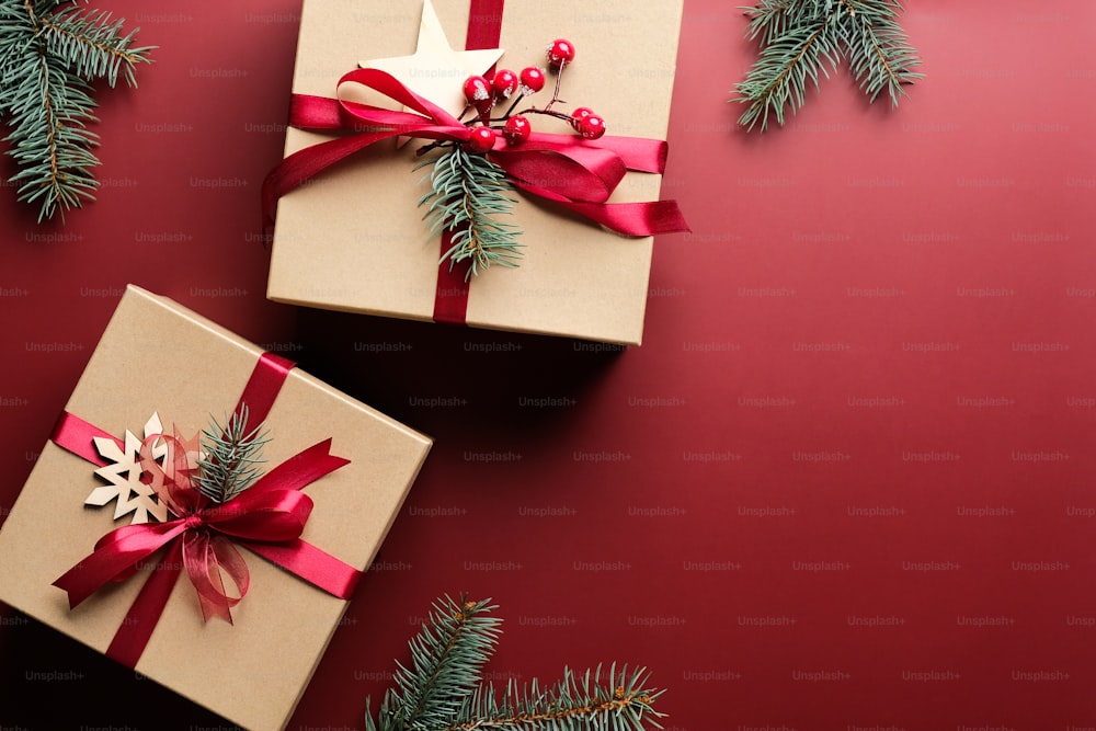Christmas gift boxes with red ribbon bow and decorations on marsala red background. Flat lay, top view. Christmas presents.