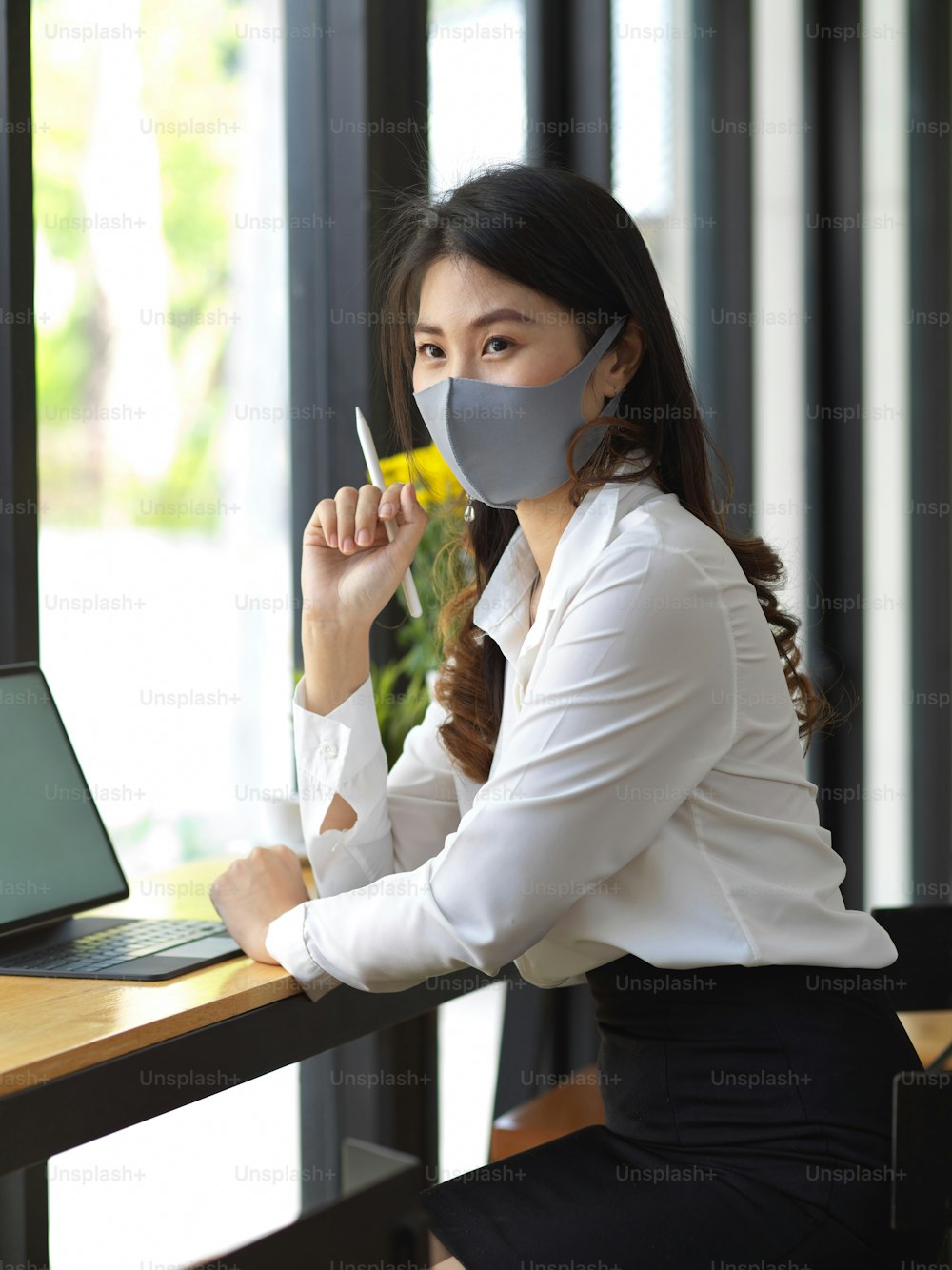 Porträt einer Frau mit Maske bei der Arbeit mit digitalem Tablet im Café