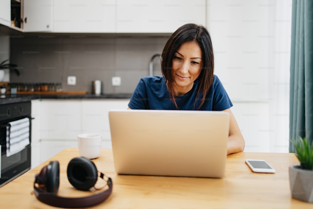 Attractive and happy middle age female freelancer is working from home during Coronavirus or Covid-19 lockdown or quarantine. Social distancing and freelancing job concept.